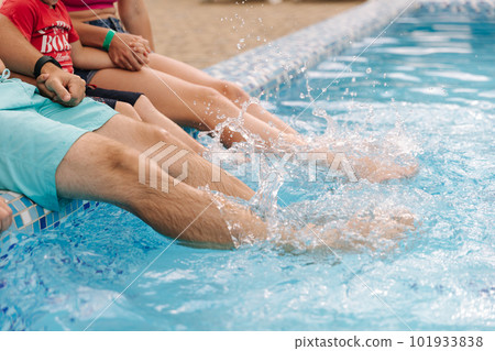 Side view of family make splashes by waving their legs in the pool.  101933838