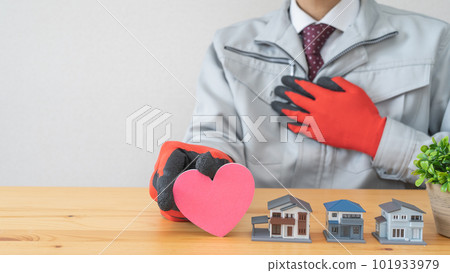 A model house and a man in work clothes, holding a heart symbol, an image of peace of mind, trust, and sincerity A model house and a man in work clothes, holding a heart symbol, an image of peace of mind, trust, and sincerity 101933979