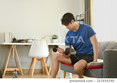 Handsome fitness man exercising with dumbbells at home. Healthy lifestyle and fitness concept 101934240