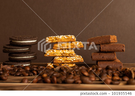 Cookies on a brown background of a burnt tree with coffee grains scattered on the table. Side view, copy space. 101935546