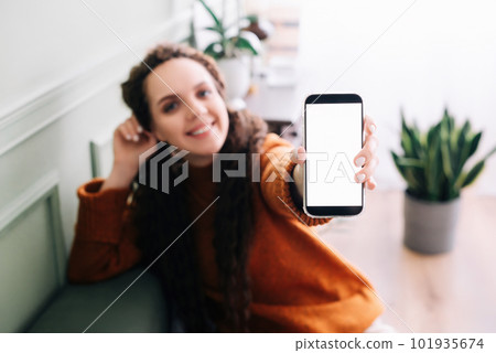 Happy young woman holding mobile phone to showcase blank display for app advertising. Smartphone Happy young woman holding mobile phone to showcase blank display for app advertising. Smartphone 101935674