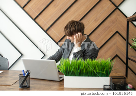 Boring job. A lazy businessman Sitting at a Laptop scratching his head Lingers in a Modern Office. 101936145