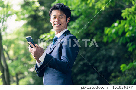 Businessman operating a smartphone in nature 101936177