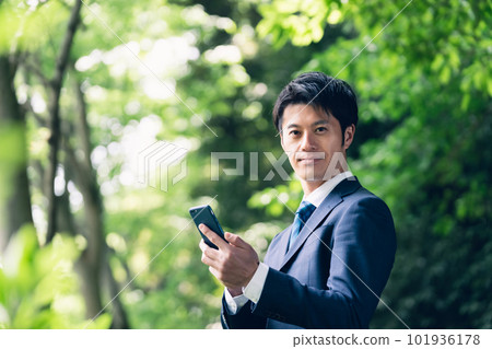 Businessman operating a smartphone in nature 101936178