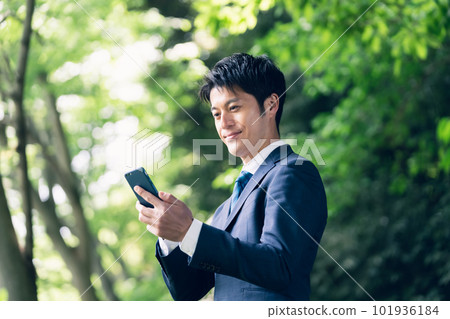 Businessman operating a smartphone in nature 101936184