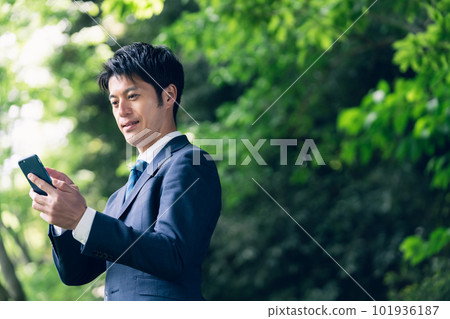 Businessman operating a smartphone in nature 101936187