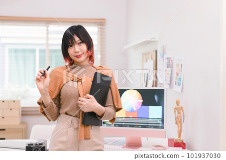 A portrait of a beautiful, professional, and confident millennial creative and stylish young female freelance designer hands holding a tablet and stylus pen while standing at her desk in office. A portrait of a beautiful, professional, and confident millennial creative and stylish young female freelance designer hands holding a tablet and stylus pen while standing at her desk in office. 101937030