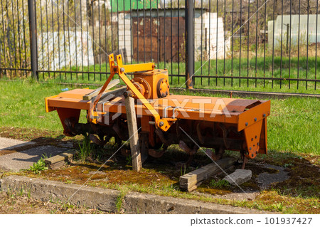 A cultivator trailer with ridges and rollers stands on the site of a store selling agricultural equipment. A cultivator trailer with ridges and rollers stands on the site of a store selling agricultural equipment. 101937427