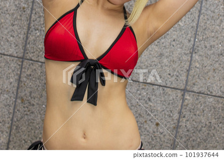 A woman in a red bikini swimsuit raises her arms and poses A woman in a red bikini swimsuit raises her arms and poses 101937644