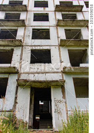 A damaged abandoned panel house with decorative facade of small white tiles. 101939058