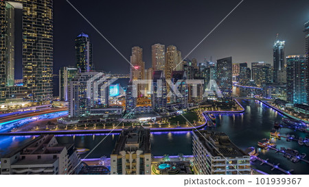 Panorama showing Dubai Marina with several boat and yachts parked in harbor and skyscrapers around canal aerial night timelapse. 101939367