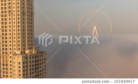 Bluewaters island with modern architecture and ferris wheel covered by morning fog aerial timelapse. Bluewaters island with modern architecture and ferris wheel covered by morning fog aerial timelapse. 101939417