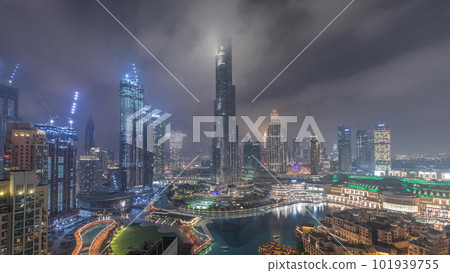 Skyscrapers rising above Dubai downtown night timelapse surrounded by modern buildings aerial top view 101939755
