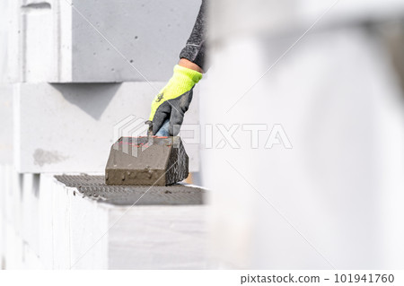 application of cement glue on concrete blocks. construction of a wall of concrete bricks 101941760