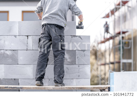 a mason builds the wall of a building from concrete bricks and blocks a mason builds the wall of a building from concrete bricks and blocks 101941772
