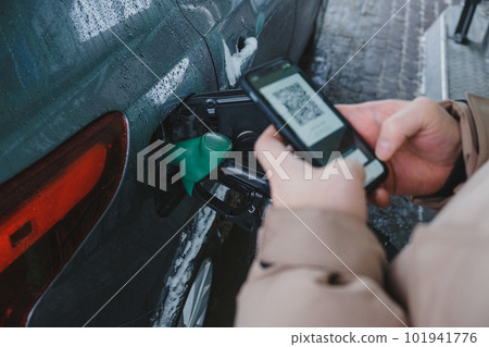 A guy uses his smartphone to pay for gas and fill up his car A guy uses his smartphone to pay for gas and fill up his car 101941776
