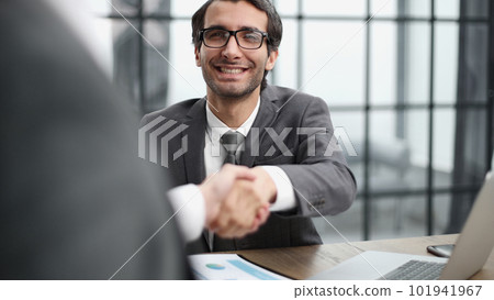 Two positive confident businessmen shaking hands over meeting table after negotiation, 101941967