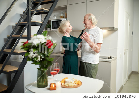 Beautiful, smiling, happy senior couple, man and woman celebrating marriage anniversary, dancing at home. Flowers and presents Beautiful, smiling, happy senior couple, man and woman celebrating marriage anniversary, dancing at home. Flowers and presents 101943876