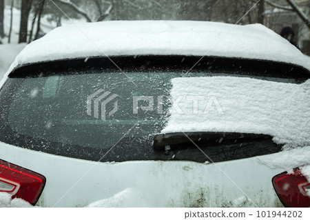 the back door of a crossover half of the window covered with a layer of snow, part of the window is clean, a close-up view of the rear of the vehicle on a winter cold day. the back door of a crossover half of the window covered with a layer of snow, part of the window is clean, a close-up view of the rear of the vehicle on a winter cold day. 101944202