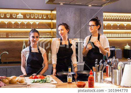 Three funny professional female chefs preparing food in large kitchen and having fun 101944770