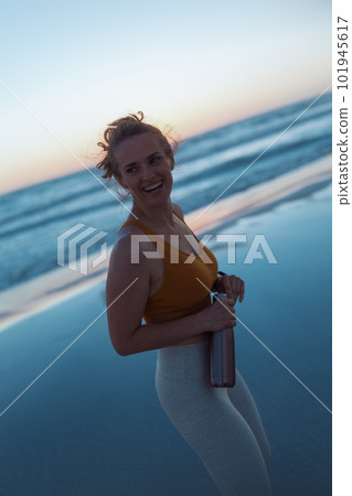 smiling fit woman jogger walking at beach at sunset 101945617