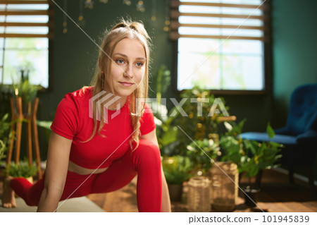 woman in red fitness clothes at green home doing yoga 101945839