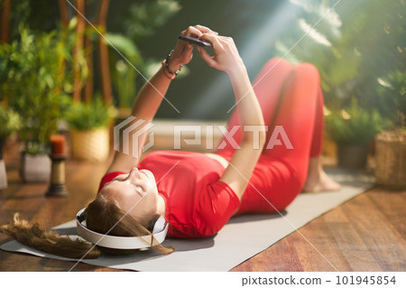 female at green home using phone and listening to music 101945854