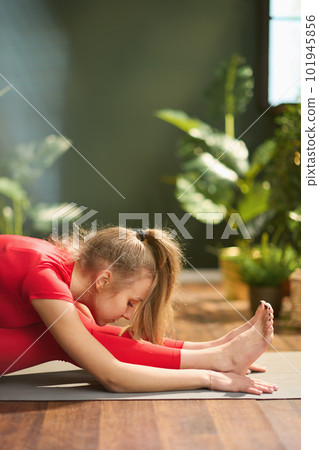 female in red fitness clothes in green living room doing yoga female in red fitness clothes in green living room doing yoga 101945856
