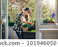 Smiling woman gardening on her balcony with cat 101946050