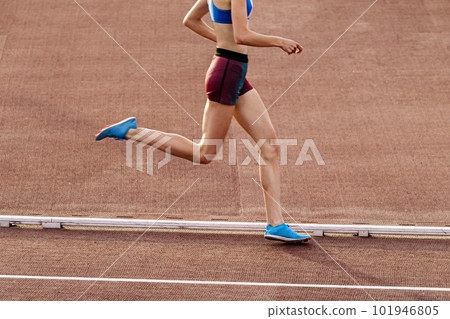 slender young female runner middle-distance running at stadium in summer athletics championships slender young female runner middle-distance running at stadium in summer athletics championships 101946805