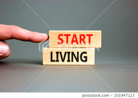 Start living symbol. Concept words Start living on beautiful wooden block. Beautiful grey table grey background. Businessman hand. Business and Start living concept. Copy space. Start living symbol. Concept words Start living on beautiful wooden block. Beautiful grey table grey background. Businessman hand. Business and Start living concept. Copy space. 101947123