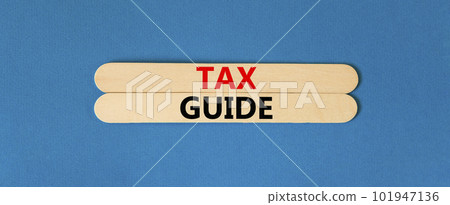 Tax guide symbol. Concept words Tax guide on beautiful wooden stick. Beautiful blue table blue background. Business and Tax guide concept. Copy space. Tax guide symbol. Concept words Tax guide on beautiful wooden stick. Beautiful blue table blue background. Business and Tax guide concept. Copy space. 101947136