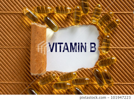 The text 'vitamin b' appearing behind torn brown paper. Yellow pills. Concept. Beautiful background. The text 'vitamin b' appearing behind torn brown paper. Yellow pills. Concept. Beautiful background. 101947223