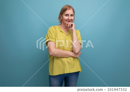 thoughtful blonde mature woman in yellow t-shirt with emotions of surprise 101947332