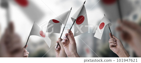 A group of people holding small flags of the Japan in their hands A group of people holding small flags of the Japan in their hands 101947621