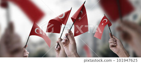 A group of people holding small flags of the Turkey in their hands A group of people holding small flags of the Turkey in their hands 101947625