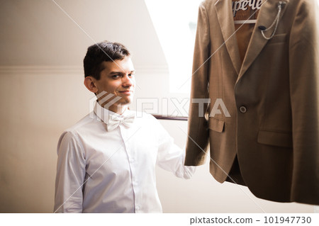 Grooms morning preparation. Handsome man getting dressed and preparing for the wedding Grooms morning preparation. Handsome man getting dressed and preparing for the wedding 101947730