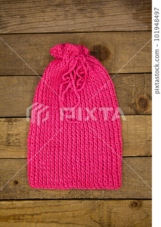 Handmade wool knitted winter pink hat and scarf on wood background Handmade wool knitted winter pink hat and scarf on wood background 101948497