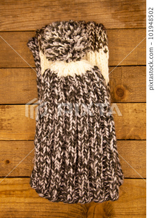 Handmade wool knitted winter grey and white hat and scarf on wood background 101948502