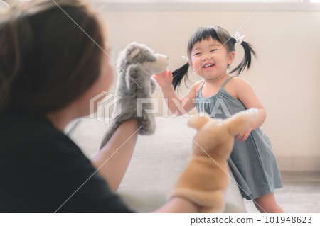 Asian mother and daughter playing animal hand puppet doll toys, sitting on couch, Educational preschool games, Having fun with kid at home concept. Asian mother and daughter playing animal hand puppet doll toys, sitting on couch, Educational preschool games, Having fun with kid at home concept. 101948623