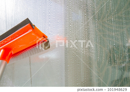 Window washing. Cleaning the window with a brush and foam. The concept of cleanliness and cleaning. Window washing. Cleaning the window with a brush and foam. The concept of cleanliness and cleaning. 101948629
