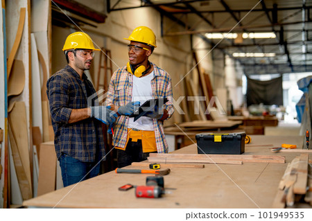 African American and Caucasian carpenter man discuss together about wood work using tablet African American and Caucasian carpenter man discuss together about wood work using tablet 101949535