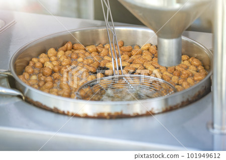 The process of cooking lokma, the cook cooks lokma in a deep fryer. Industrial production of a popular Middle Eastern dessert made from deep-fried dough balls. Little donuts. The process of cooking lokma, the cook cooks lokma in a deep fryer. Industrial production of a popular Middle Eastern dessert made from deep-fried dough balls. Little donuts. 101949612