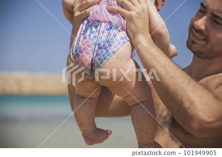 father holds newborn baby in a fish swimsuit on the beach father holds newborn baby in a fish swimsuit on the beach 101949905