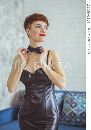 slim woman in a leather dress straightens a butterfly around her neck slim woman in a leather dress straightens a butterfly around her neck 101949957