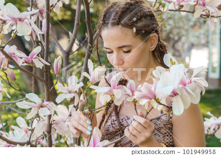Magnolia flowers, a girl smells a blooming magnolia in the park in the sun, enjoys her vacation. 101949958