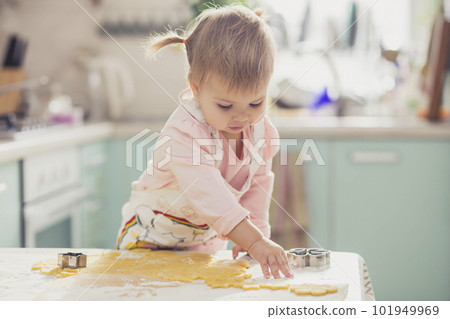 Adorable baby in an apron makes cookies from dough in the kitchen 101949969