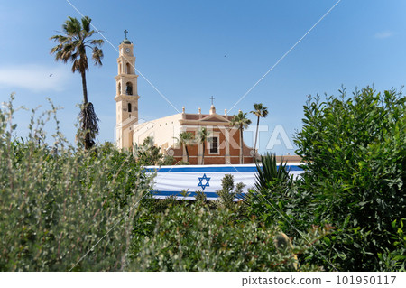 View of the St. Peter's Church in Old City of Yafo with a long israeli flag on the eve of Israel's Independence Day, Israel.St. Peter's Church is a Franciscan church in Jaffa, part of Tel Aviv, 101950117