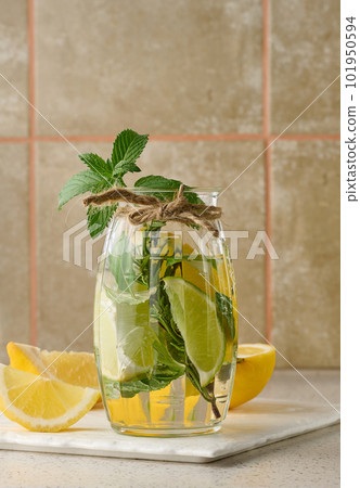 Lemonade in a transparent glass with lemon, lime, rosemary sprigs and mint leaves on a white background 101950594