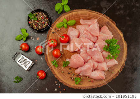 Ogranic food and healthy eating.chicken fillet.Fresh pieces of turkey meat.Raw chicken.Raw pieces of turkey meat with herbs and tomatoes on a wooden board on a black background.Close up. 101951193